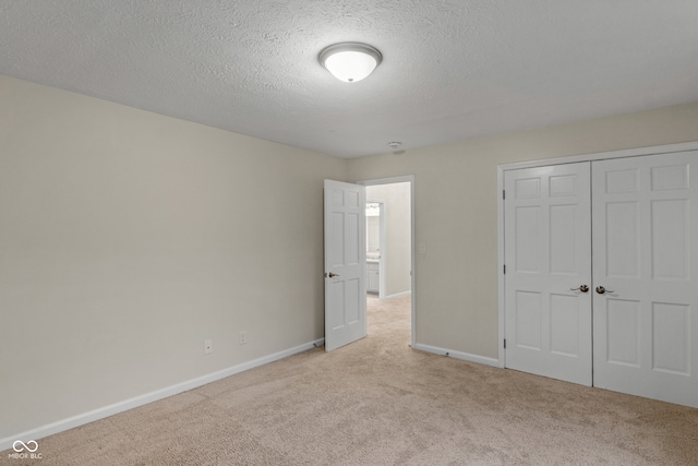 unfurnished bedroom with a textured ceiling, light carpet, and a closet