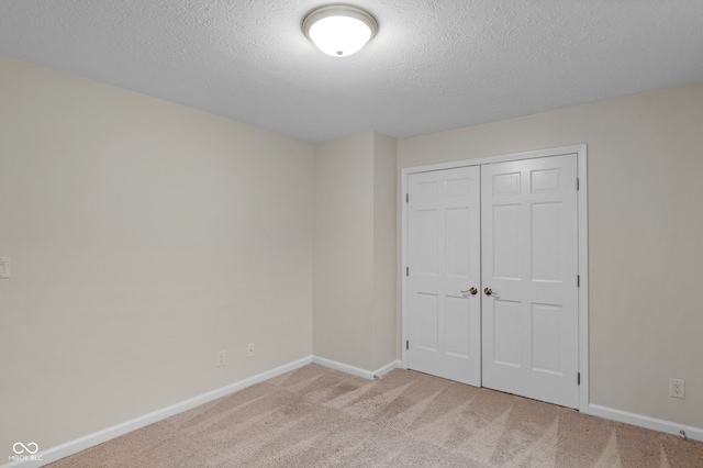 unfurnished bedroom with a textured ceiling, light carpet, and a closet