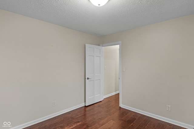 spare room featuring a textured ceiling and dark wood-type flooring