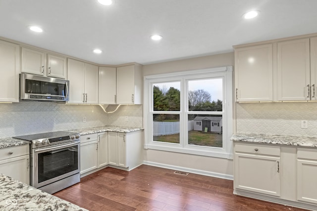 kitchen featuring decorative backsplash, dark hardwood / wood-style flooring, light stone countertops, and stainless steel appliances