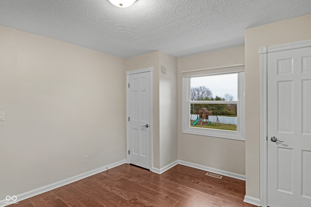 unfurnished bedroom featuring a textured ceiling and dark hardwood / wood-style floors