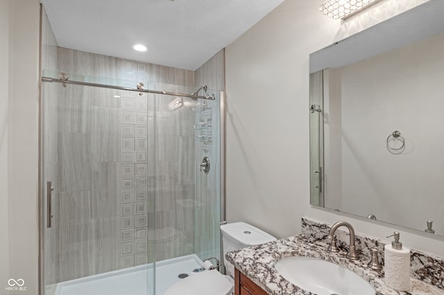 bathroom with a textured ceiling, vanity, toilet, and walk in shower