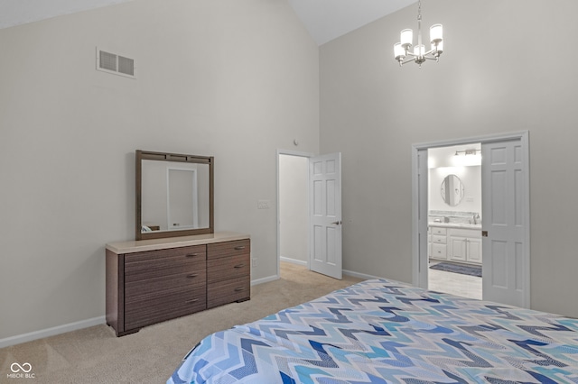 carpeted bedroom featuring an inviting chandelier, high vaulted ceiling, and ensuite bath