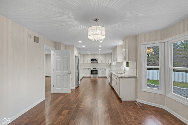 kitchen featuring sink, hanging light fixtures, dark hardwood / wood-style floors, appliances with stainless steel finishes, and white cabinetry