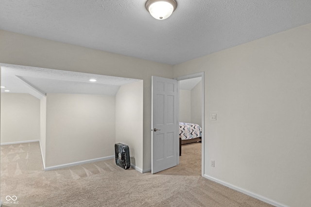 spare room with light colored carpet and a textured ceiling