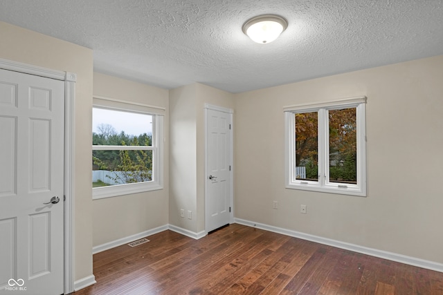 unfurnished bedroom featuring a textured ceiling and dark hardwood / wood-style floors