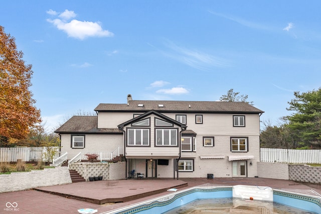 back of property featuring a fenced in pool and a patio