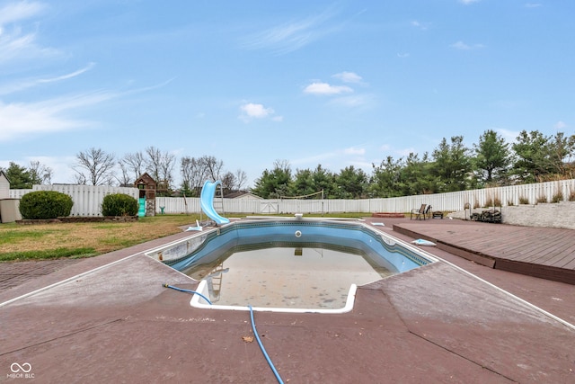 view of swimming pool featuring a lawn, a wooden deck, and a water slide