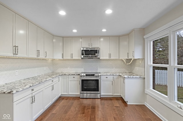 kitchen with tasteful backsplash, light stone counters, stainless steel appliances, dark hardwood / wood-style floors, and white cabinetry