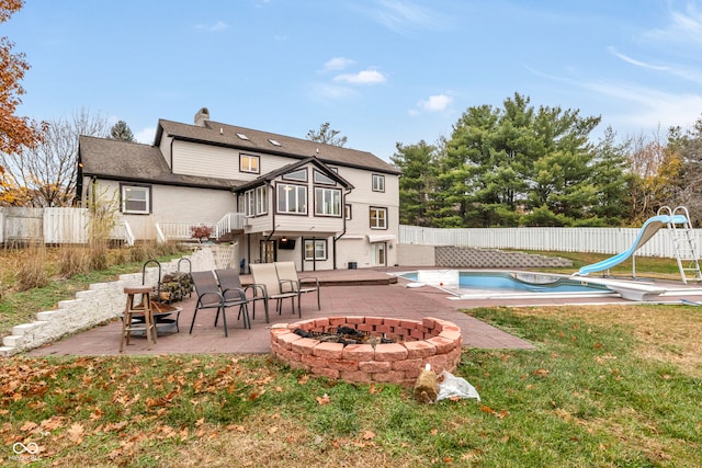 rear view of property featuring a yard, a patio, a fenced in pool, and an outdoor fire pit