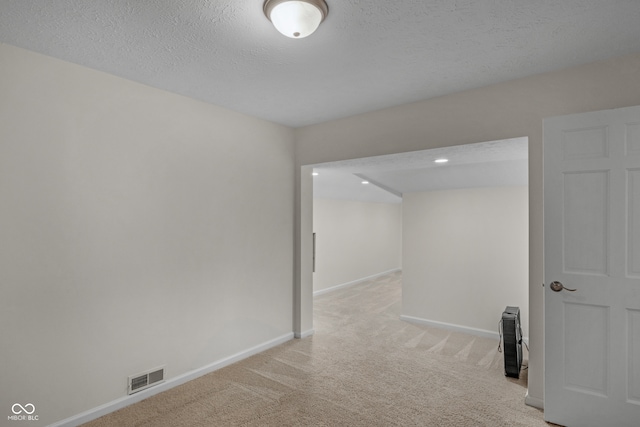 unfurnished room with light carpet and a textured ceiling