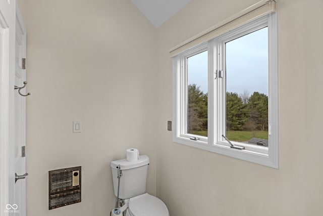 bathroom featuring heating unit, vaulted ceiling, and toilet