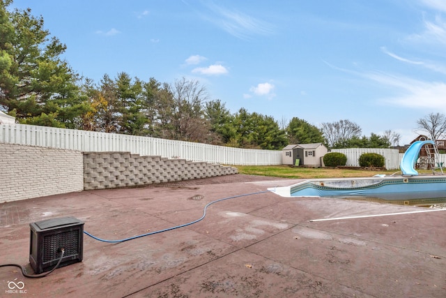 view of swimming pool featuring a storage unit, a patio area, and a water slide