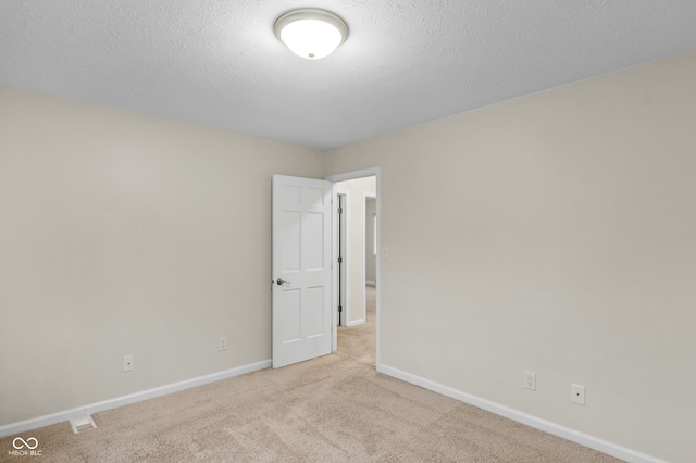 unfurnished room with light carpet and a textured ceiling