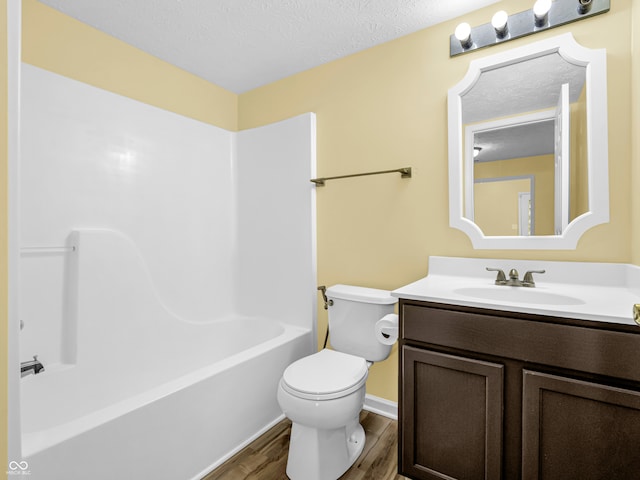 full bathroom with vanity, a textured ceiling, hardwood / wood-style flooring, washtub / shower combination, and toilet