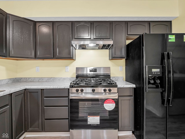 kitchen featuring dark brown cabinets, black fridge, and stainless steel gas range oven