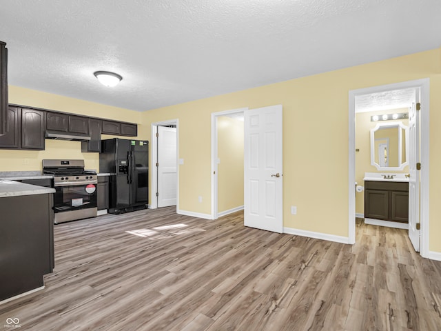 kitchen featuring stainless steel gas range oven, black fridge with ice dispenser, dark brown cabinets, a textured ceiling, and light hardwood / wood-style floors