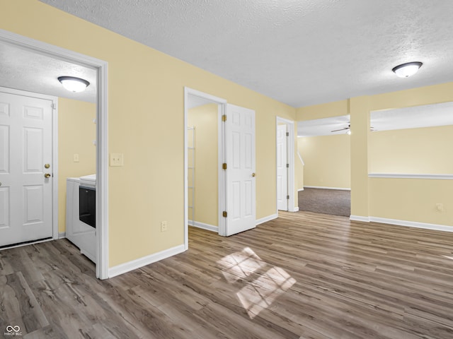 unfurnished room featuring hardwood / wood-style flooring, a textured ceiling, and washing machine and clothes dryer