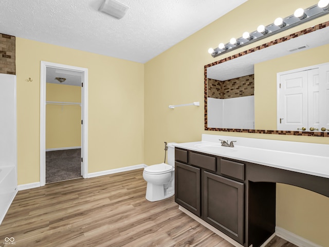 bathroom with vanity, hardwood / wood-style floors, a textured ceiling, and toilet