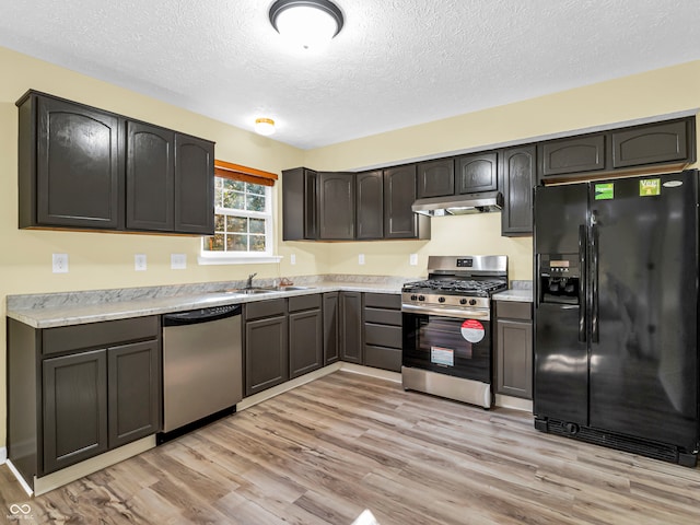 kitchen with sink, light wood-type flooring, a textured ceiling, dark brown cabinetry, and stainless steel appliances