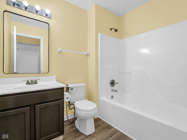 full bathroom with hardwood / wood-style floors, a textured ceiling, toilet, shower / washtub combination, and vanity