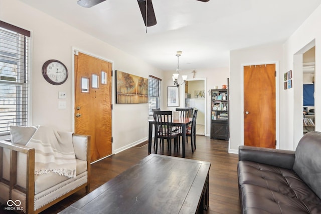 living room featuring dark hardwood / wood-style flooring, ceiling fan with notable chandelier, and a healthy amount of sunlight