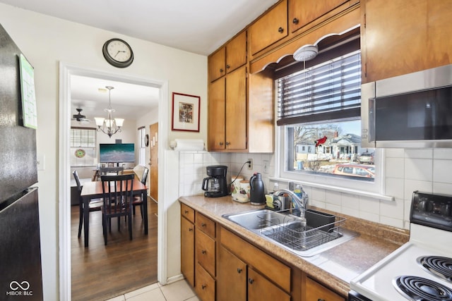 kitchen with range with electric stovetop, sink, backsplash, a chandelier, and light tile patterned floors