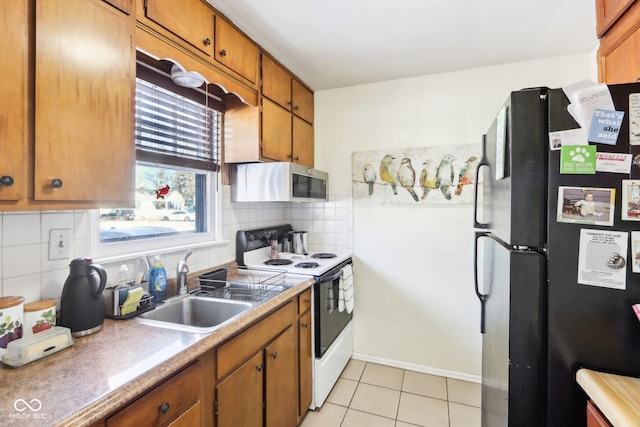 kitchen with black fridge, white electric stove, decorative backsplash, and light tile patterned floors