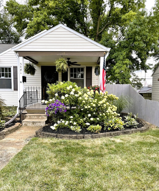 bungalow with a porch, fence, a front lawn, and ceiling fan