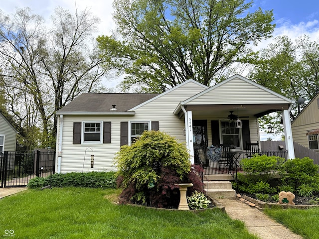bungalow-style home featuring a porch, ceiling fan, fence, and a front lawn