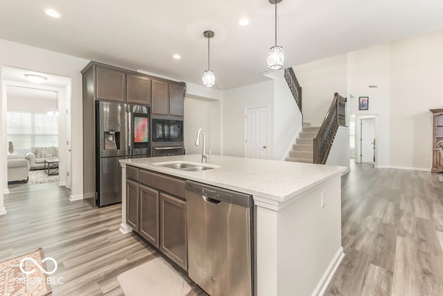 kitchen featuring dark brown cabinets, stainless steel appliances, sink, decorative light fixtures, and light hardwood / wood-style floors