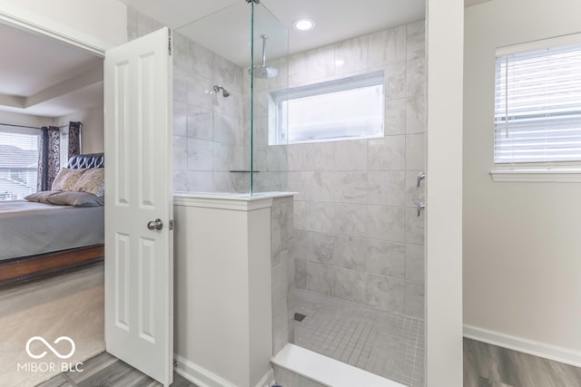 bathroom with tiled shower, hardwood / wood-style flooring, and a wealth of natural light