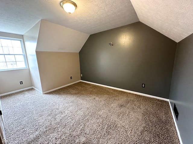 bonus room with carpet flooring, lofted ceiling, and a textured ceiling