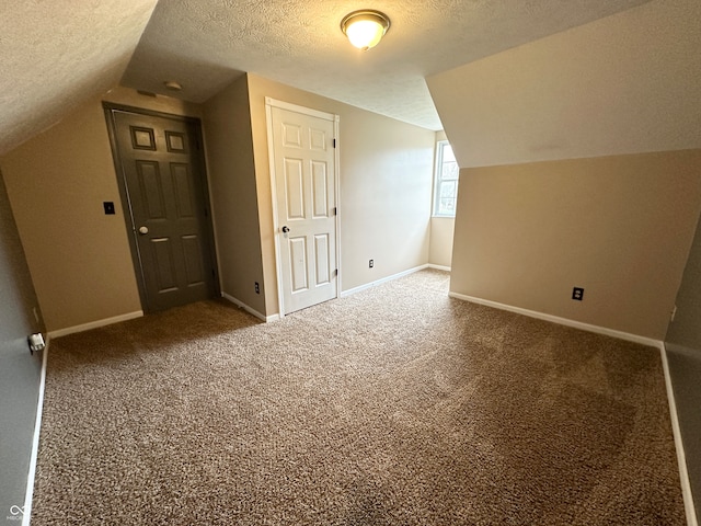 additional living space with a textured ceiling, carpet floors, and vaulted ceiling