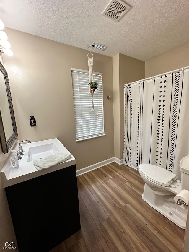 bathroom with hardwood / wood-style floors, vanity, toilet, and a textured ceiling