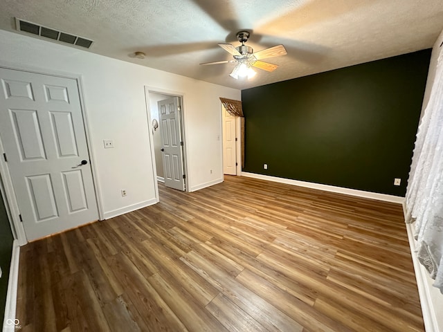 unfurnished bedroom featuring wood-type flooring, a textured ceiling, and ceiling fan