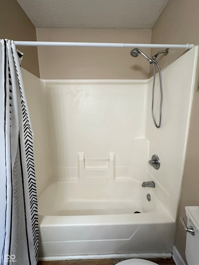 bathroom with toilet, a textured ceiling, and shower / tub combo with curtain