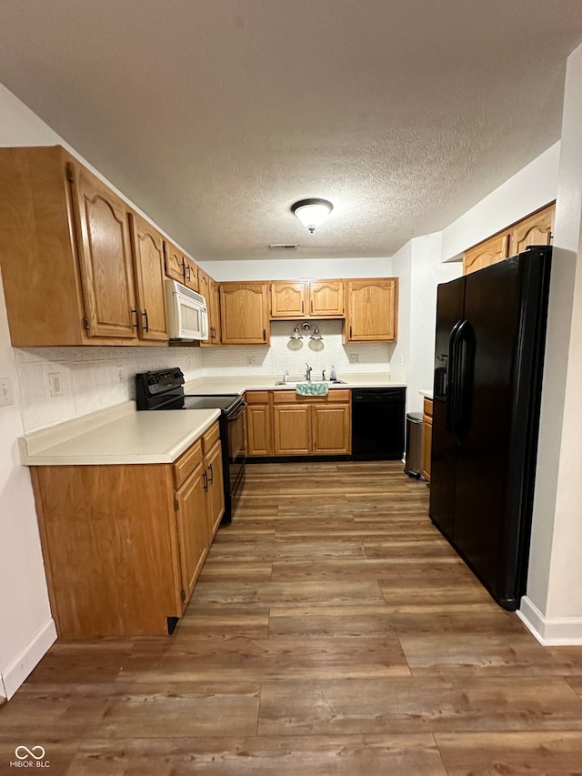 kitchen featuring black appliances, dark hardwood / wood-style flooring, sink, and a textured ceiling