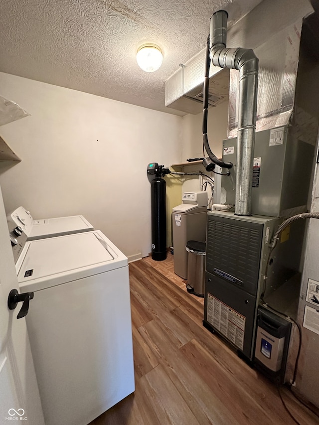 laundry room featuring washing machine and clothes dryer, heating unit, dark hardwood / wood-style flooring, and a textured ceiling