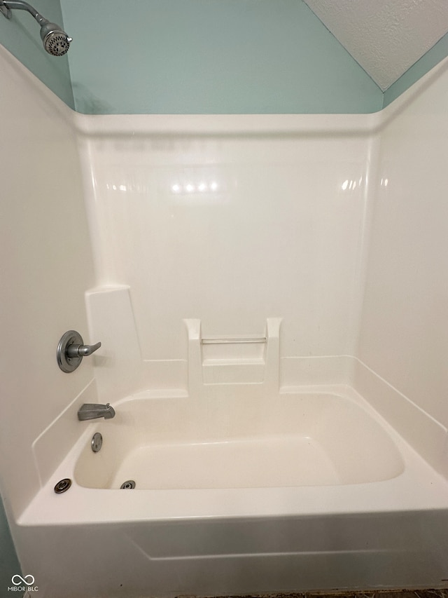 bathroom featuring bathtub / shower combination and a textured ceiling