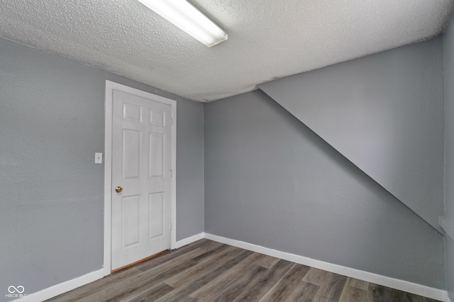 bonus room with a textured ceiling and dark hardwood / wood-style flooring