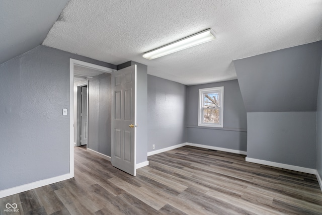 bonus room featuring wood-type flooring, a textured ceiling, and vaulted ceiling