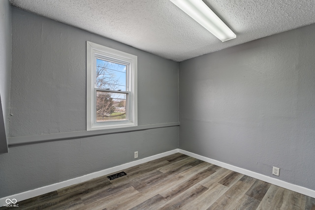 unfurnished room featuring a textured ceiling and hardwood / wood-style flooring