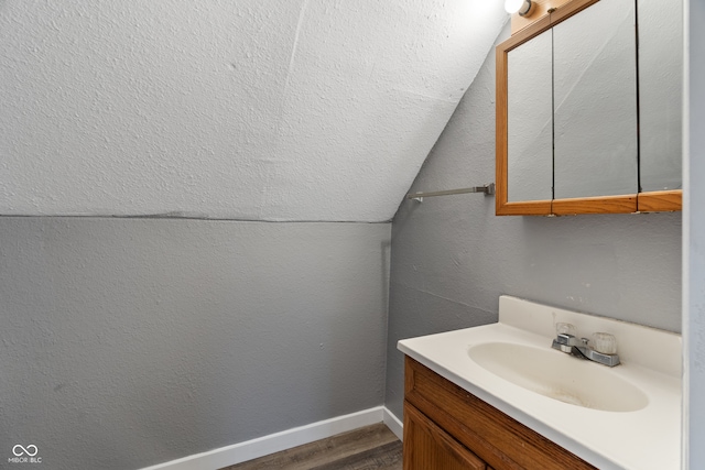 bathroom featuring hardwood / wood-style flooring, vanity, and lofted ceiling