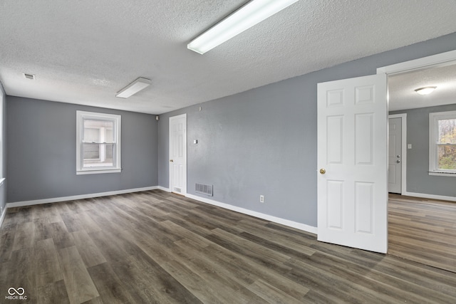 empty room featuring dark wood-type flooring and a textured ceiling