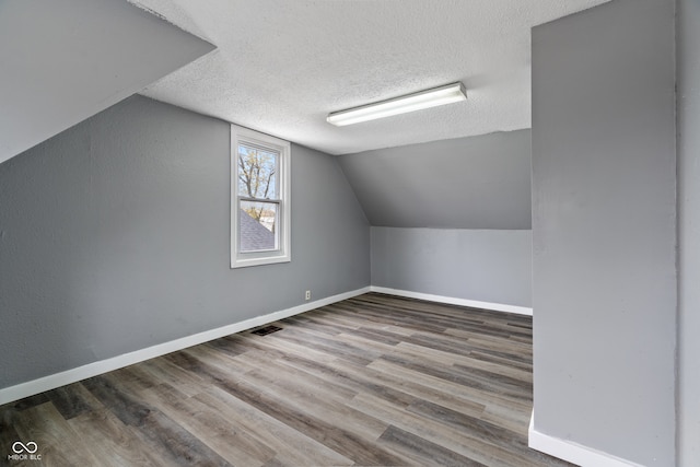 bonus room featuring wood-type flooring, a textured ceiling, and lofted ceiling