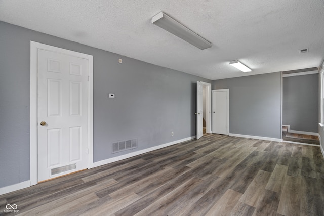 spare room with dark wood-type flooring and a textured ceiling