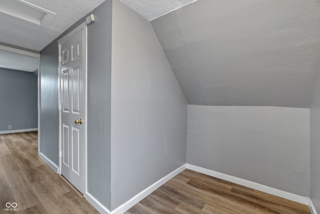 bonus room featuring hardwood / wood-style floors, a textured ceiling, and vaulted ceiling