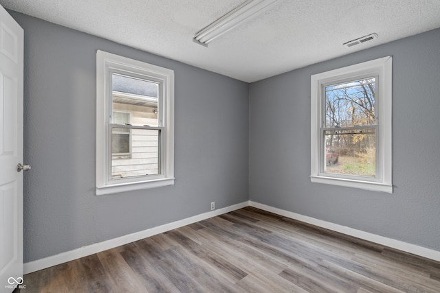 spare room featuring hardwood / wood-style floors and a textured ceiling