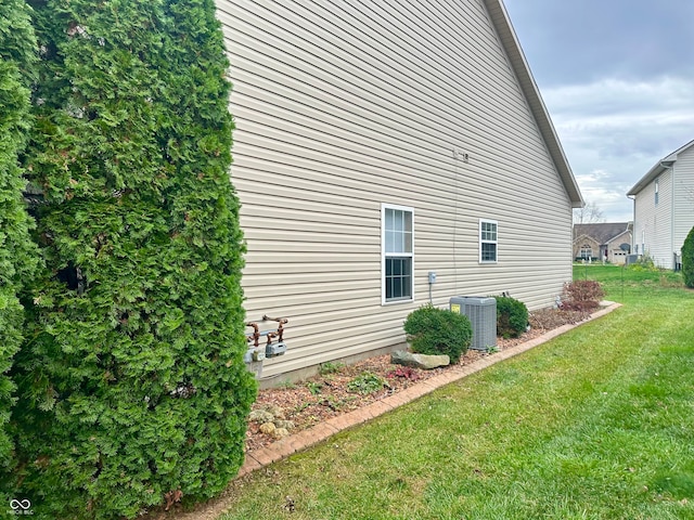 view of side of property featuring a lawn and central air condition unit